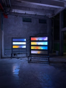 Two glowing light boxes with color gradients in a dark industrial space