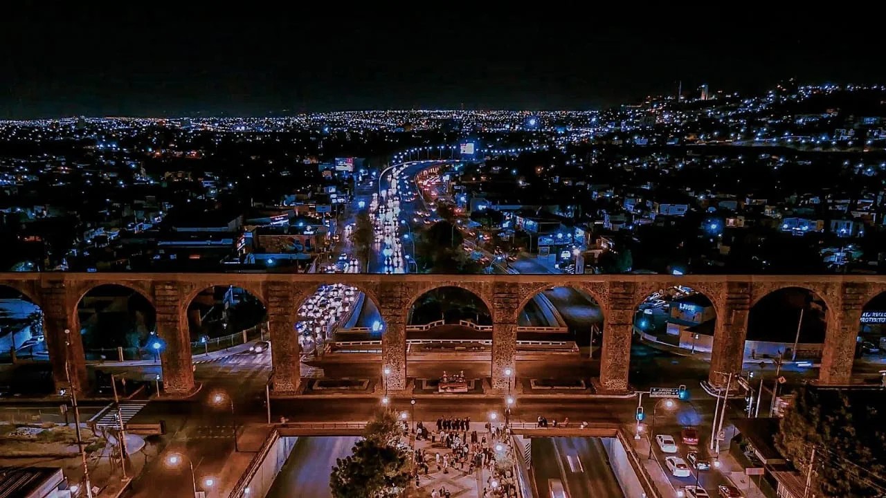The Querétaro aqueduct at night, with the city lights behind